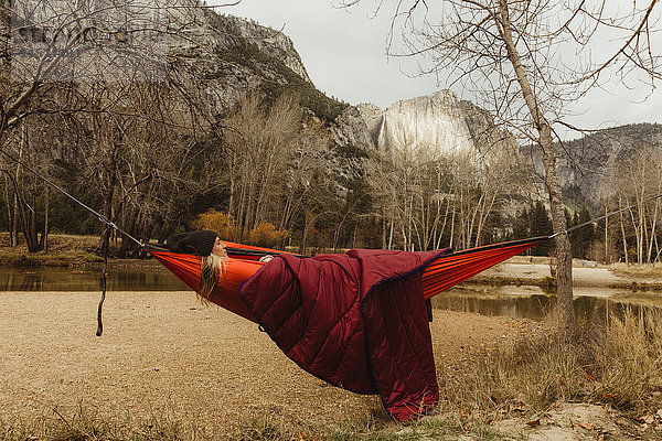 In roter Hängematte liegende Frau mit Blick auf die Landschaft  Yosemite National Park  Kalifornien  USA