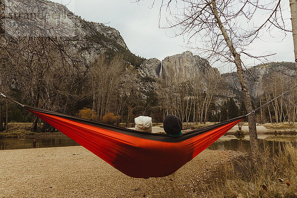 Rückansicht eines in roter Hängematte liegenden Paares mit Blick auf die Landschaft  Yosemite National Park  Kalifornien  USA