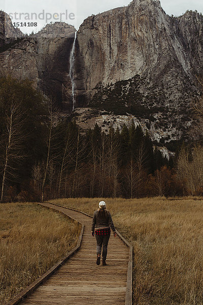 Rückansicht einer Wanderin  die auf einer Strandpromenade in Richtung Berge wandert  Yosemite National Park  Kalifornien  USA