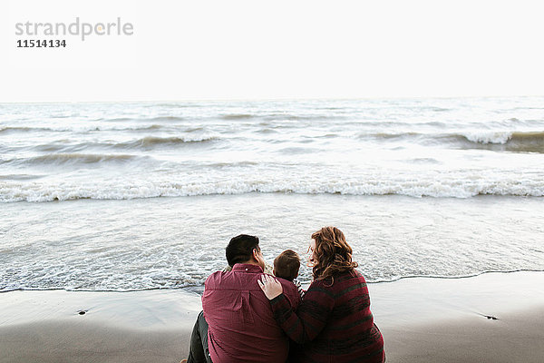 Rückansicht von Mutter und Vater am Strand sitzend