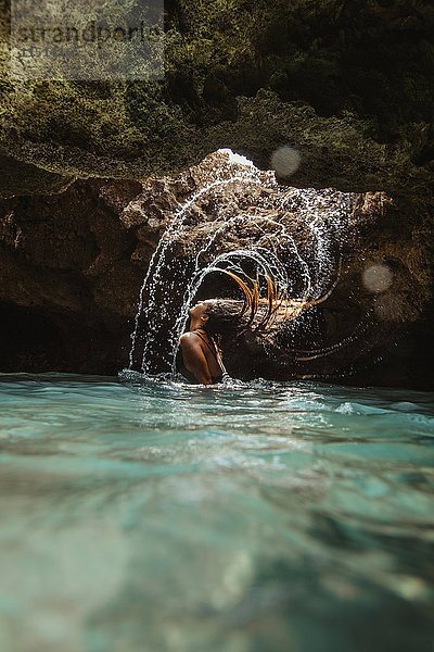 Frau in wassergefüllter Höhle  die nasses Haar zurückwirft  spritzend  Oahu  Hawaii  USA