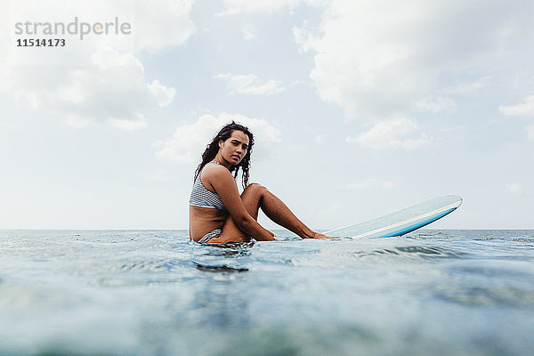 Oberflächenansicht einer Frau auf einem Surfbrett  die in die Kamera schaut  Oahu  Hawaii  USA