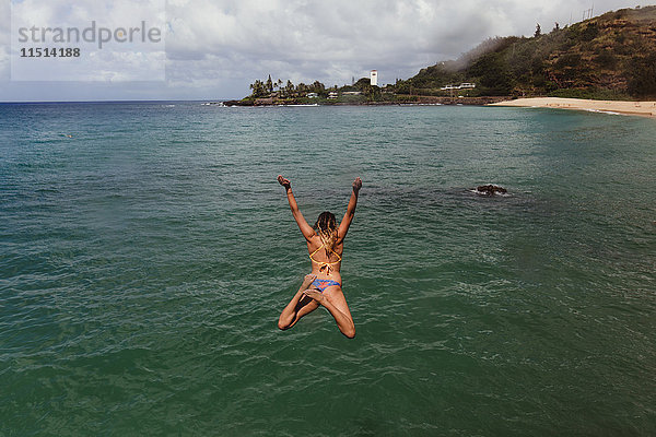 Rückansicht einer Frau  die ins Meer springt  Oahu  Hawaii  USA