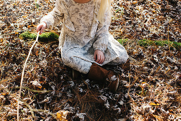 Mädchen hält Stock im Wald