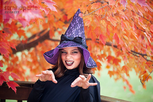 Als Hexe verkleidetes Mädchen macht zu Halloween ein Gesicht