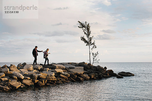Junges Paar geht auf Felsen am Meer