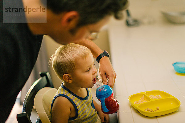 Vater hilft kleinem Sohn beim Essen