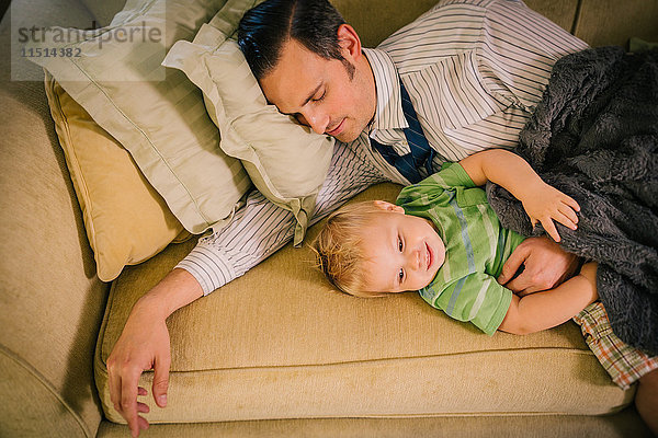 Vater und kleiner Sohn liegen zusammen auf dem Sofa