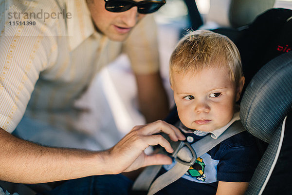 Vater sichert kleinen Sohn im Autositz