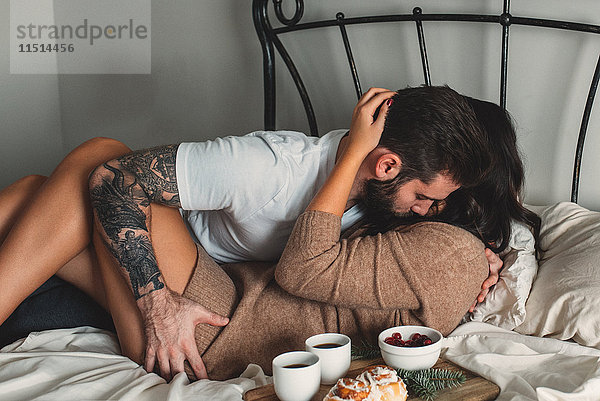 Leidenschaftliches junges Paar mit Frühstück im Bett