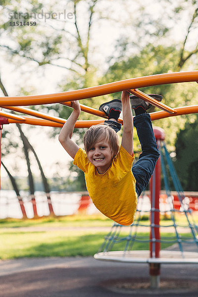 Porträt eines Jungen  der am Klettergerüst des Parks hängt