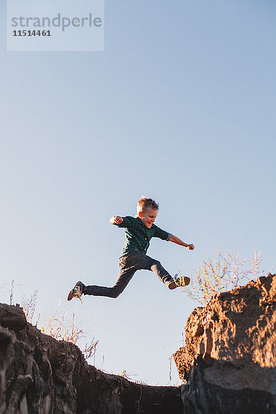 Junge springt in der Luft über Klippenränder