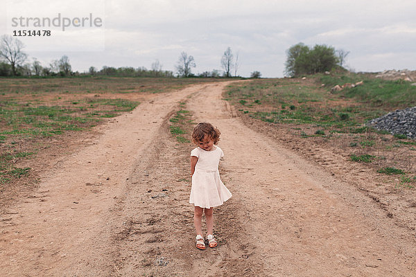Porträt eines schüchternen Mädchens  das auf einem ländlichen Feldweg steht