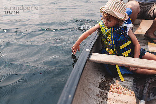 Mädchen berührt Wasser aus Ruderboot auf See
