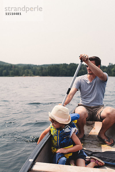 Junger Mann und Tochter rudern im Ruderboot über den See