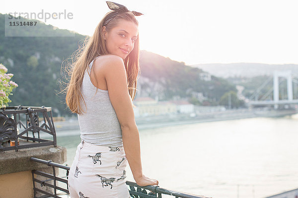 Porträt einer jungen Frau im Rückblick auf der Dachterrasse am Wasser  Budapest  Ungarn
