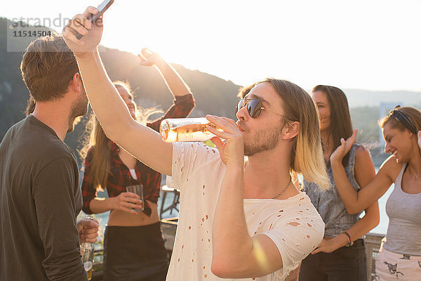 Junger Mann beim Biertrinken auf einer Dachterrassenparty am Hafen  Budapest  Ungarn