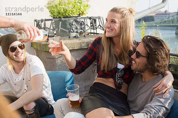 Erwachsene Freunde entspannen sich und schenken Wein ein bei einer Dachterrassenparty