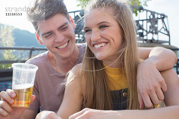 Junges Paar mit Getränken bei Dachterrassenparty