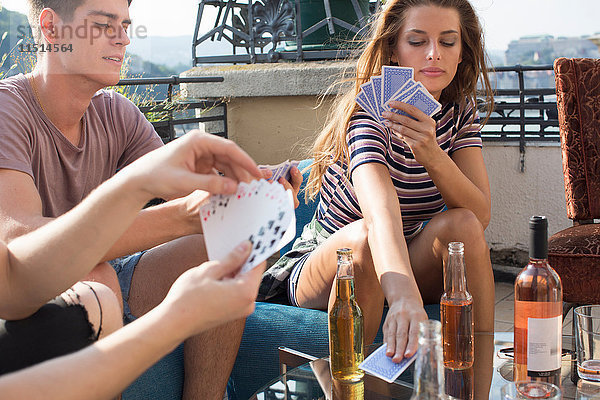 Junge erwachsene Freunde spielen Kartenspiele auf der Dachterrassenparty