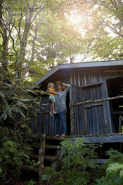 Mutter und Tochter stehen vor der Holzhütte