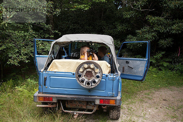 Junges Mädchen schaut aus einem Geländewagen heraus und benutzt ein Fernglas