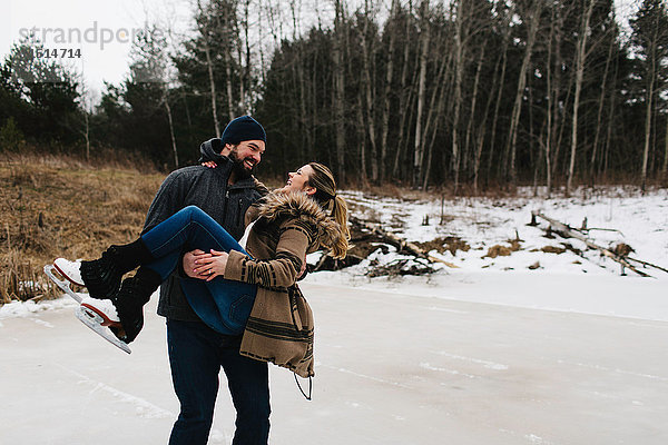 Mann läuft Schlittschuh mit Frau im Arm  Whitby  Ontario  Kanada