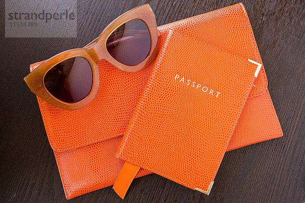 Draufsicht auf orangefarbene Geldbörse  Reisepass und Sonnenbrille