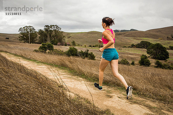 Läuferin läuft auf Feldweg in der Landschaft