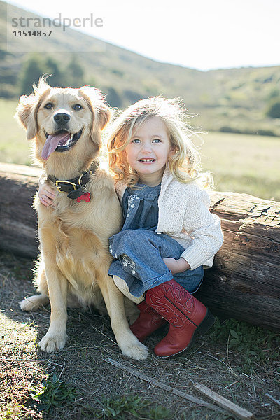 Porträt von Mädchen und Hund sitzend am Baumstamm