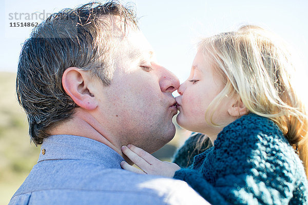 Seitenansicht eines mittleren Erwachsenen  der seine Tochter küsst