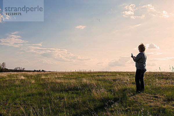 Reife Frau steht in Feldlandschaft und schaut auf ein Smartphone in der Nähe von Hastings Nebraska  USA