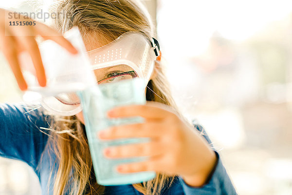 Mädchen macht wissenschaftliches Experiment  gießt Flüssigkeit ein