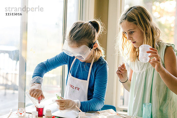 Zwei Mädchen machen ein wissenschaftliches Experiment  mit roter Flüssigkeit