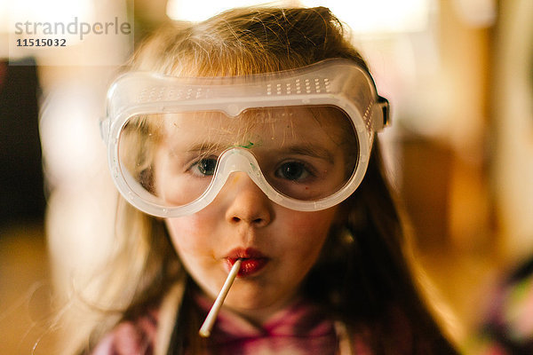 Porträt eines Mädchens mit Schutzbrille beim Lutschen eines Lutschers