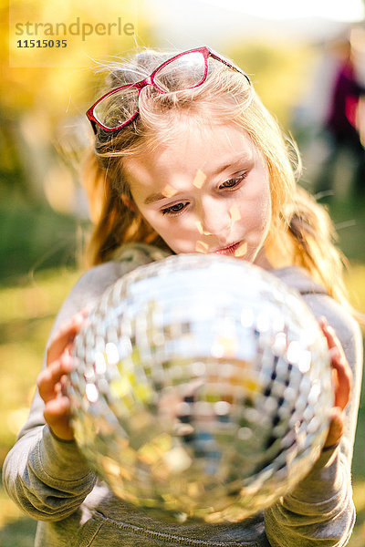 Mädchen im sonnenbeschienenen Garten  das auf die Discokugel starrt