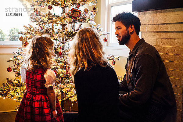Rückansicht eines weiblichen Kleinkindes mit Eltern  die den Weihnachtsbaum betrachten