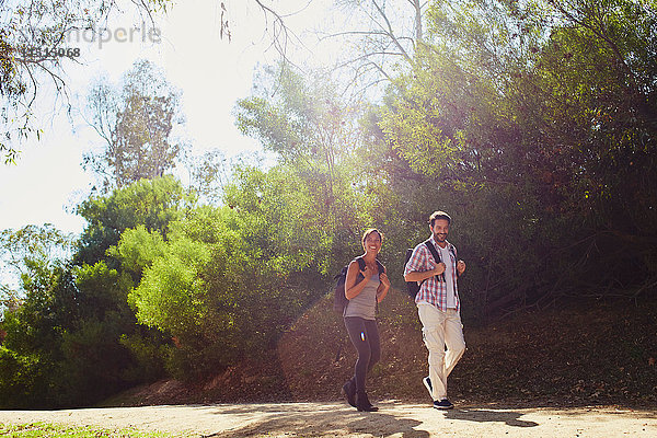 Mittleres erwachsenes Paar beim Wandern  Spaziergang entlang der sonnenbeschienenen Landstraße