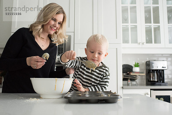 Mutter und Sohn backen zusammen und geben die Mischung in das Backblech.