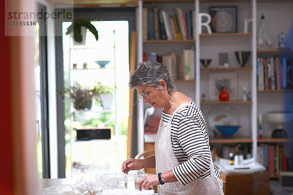Ältere Frau in der Küche  die klare Töpfe auf der Arbeitsfläche anordnet
