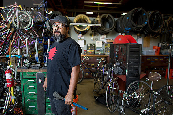 Porträt eines reifen Mannes mit Schraubenschlüssel in einer Fahrradwerkstatt