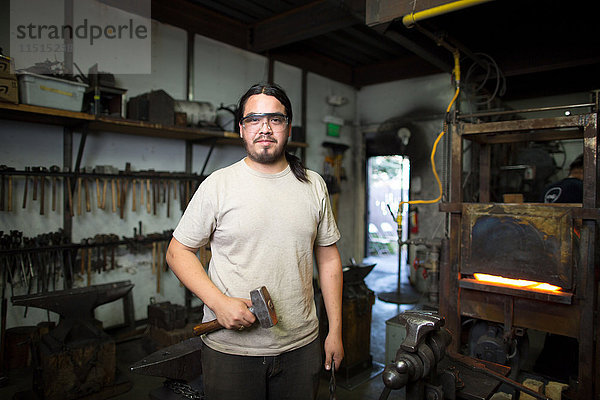 Porträt eines männlichen Metallschmieds am Ofen der Metallwerkstatt