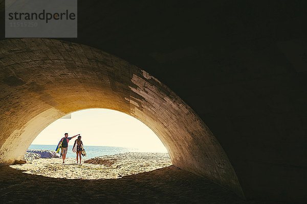 Surferpaar beim Gang durch die Strandunterführung  Newport Beach  Kalifornien  USA