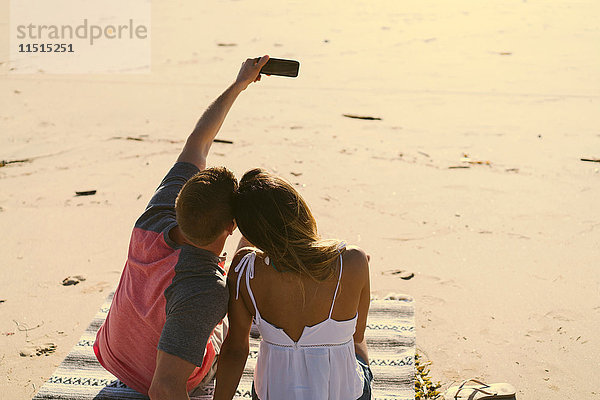 Rückansicht eines am Strand sitzenden Paares mit Smartphone-Selfie  Newport Beach  Kalifornien  USA