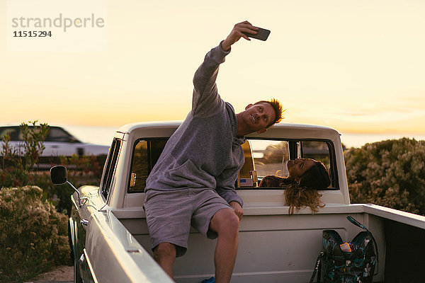 Mann nimmt Smartphone-Selfie mit Freundin auf dem Rücksitz eines Pickup-Trucks in Newport Beach  Kalifornien  USA