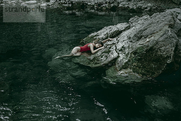 Kaukasische Frau liegt auf Felsen in einem Wasserbecken
