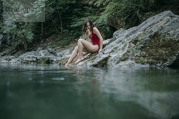 Kaukasische Frau sitzt auf Steinen an einem Wasserbecken