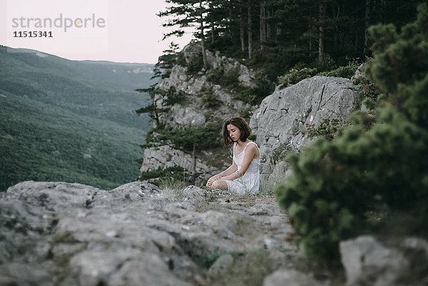 Traurige kaukasische Frau sitzt auf einem Berg