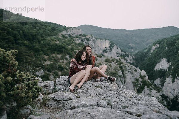 Kaukasische Frauen  die sich auf einem Berg umarmen