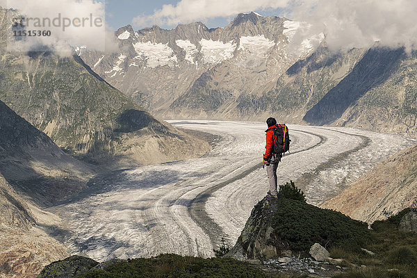 Kaukasischer Mann steht auf einem Felsen in verschneiten Bergen